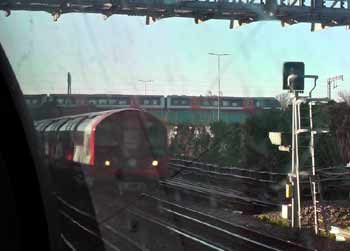 Class 710 Overground train crosses a bridge over a Central line 1992ts train near Leytonstone.